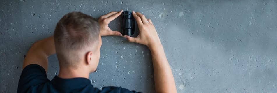 Veillance technician installing an Ajax device on a wall