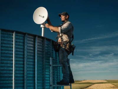 Technician installing a point-to-point wireless link antenna on a grain bin